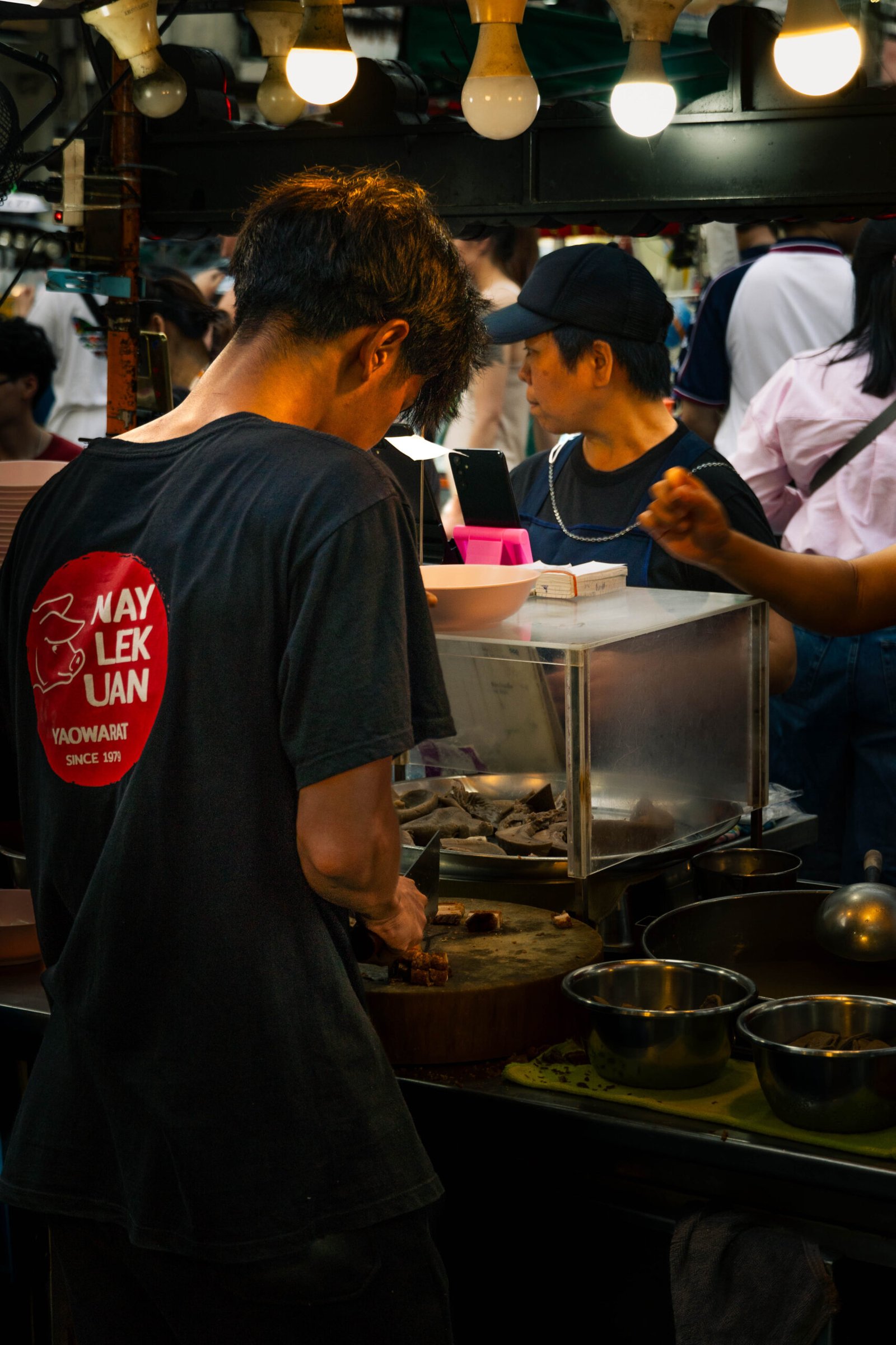 Profesjonalna fotografia mężczyzny gotującego tajskie potrawy street food w Bangkoku – dynamiczna scena kulinarna