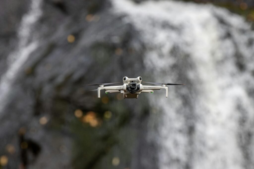 A drone captured mid-flight against a stunning waterfall backdrop in Sweden, showcasing technology in nature.