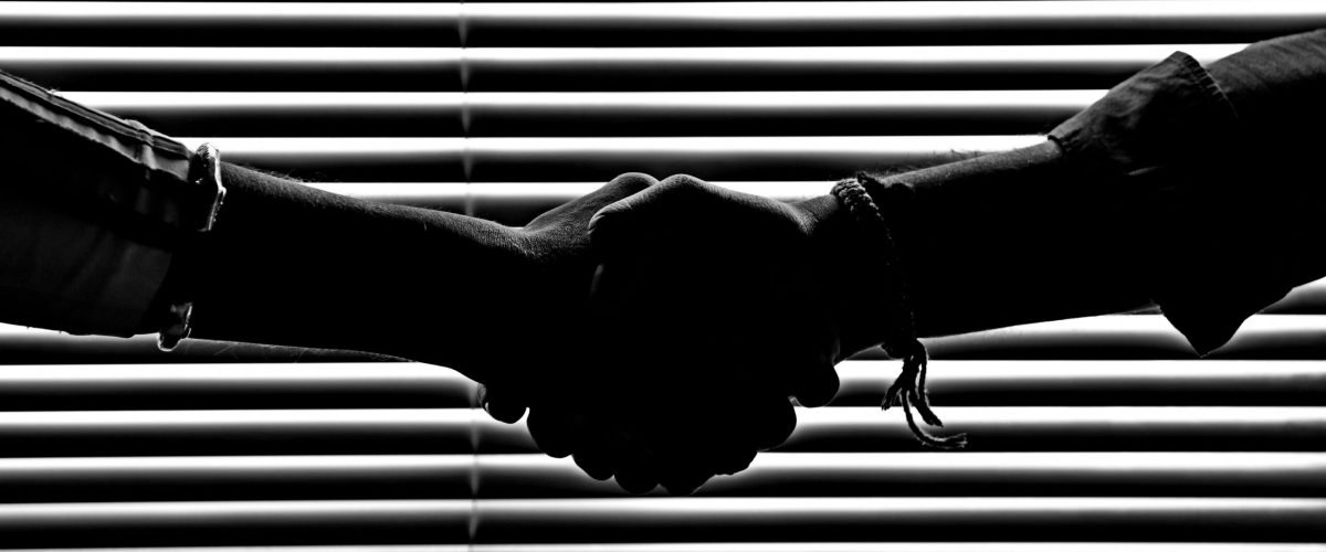 Silhouette of two people shaking hands symbolizing partnership and trust.